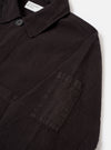 The Licorice Lyo Linen Mix Coverall Jacket is shown from the back as a flat lay against a plain white background. The image highlights the jacket’s short, square silhouette, straight hem, and simple, unbuttoned cuffs. The dark brown fabric has a visible linen-blend texture with clean stitching along the shoulders and sleeves.