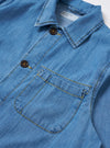 The Washed Indigo 8oz Slub Denim Field Jacket is shown from the back as a flat lay against a plain white background. The image highlights the textured character of the indigo-washed slub denim and the clean, straight-cut construction of the jacket's rear panel.