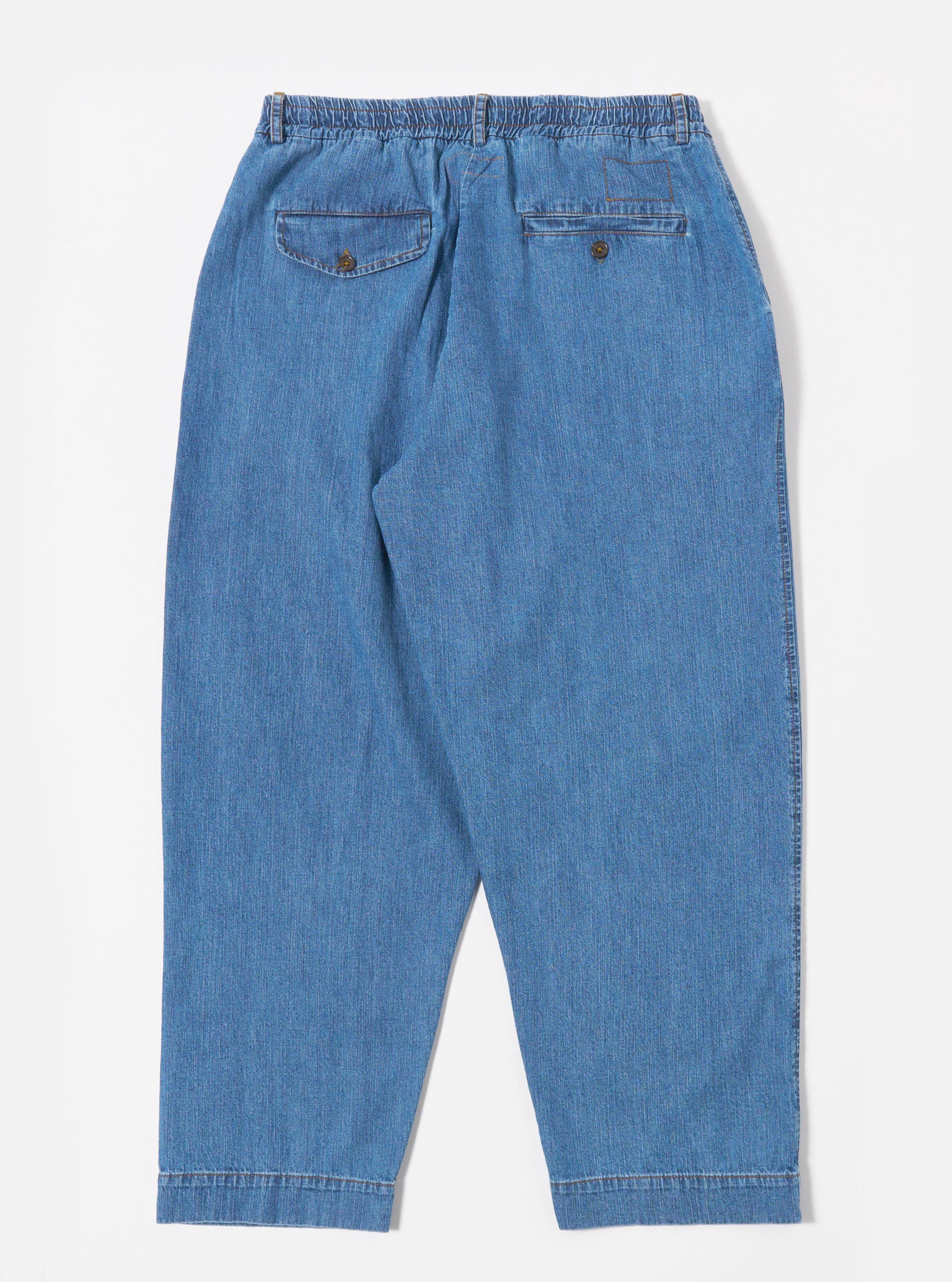 The Washed Indigo 8oz Slub Denim Oxford Pant is shown from the back as a flat lay against a plain white background. The image highlights the elasticated waistband and two rear patch pockets. The washed indigo denim fabric features a distinct slubby texture with visible white highlights.