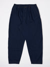 The Indigo Recycled Herringbone Pleated Track Pant is shown as a flat lay against a plain white background. The trousers feature a drawstring waistband, a single pleat on each leg, and a relaxed, tapered fit. The dark indigo fabric has a visible herringbone texture.