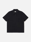 The Black Light Weight Terry Newlyn Polo is shown as a flat lay against a white background. The polo features a self-fabric collar, a two-button placket, and a single square chest pocket. The black fabric has a soft, textured terry cloth appearance with visible fine loops.