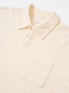 The Ecru Light Weight Terry Newlyn Polo is shown from the back as a flat lay against a plain white background. The garment features a simple, clean-cut back panel, short sleeves, and a structured polo collar. The fabric is an off-white ecru with a soft, looped terry texture.