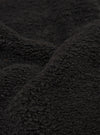 A close-up fabric swatch of the Black Alvar Fleece Lancaster Gilet highlights the thick and curly texture of the black fleece material.
