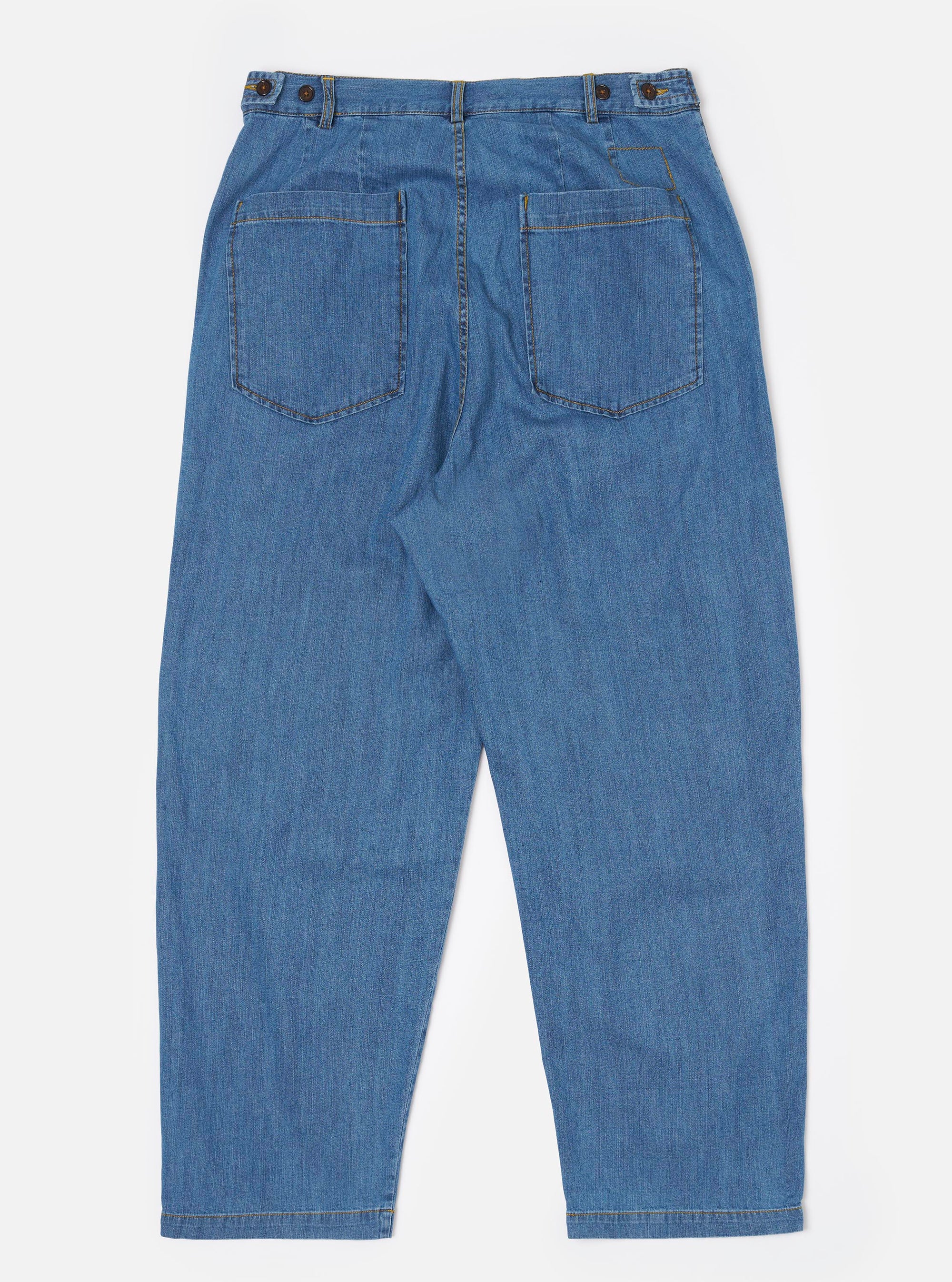 The Washed Indigo 8oz Slub Denim Dutch Pant is shown from the back as a flat lay against a plain white background. The image highlights the wide-leg silhouette, the elasticated waistband with side button adjusters, and two large rear patch pockets. The 100% recycled cotton denim features a visible slub texture and a faded indigo wash with distinct stitching details.