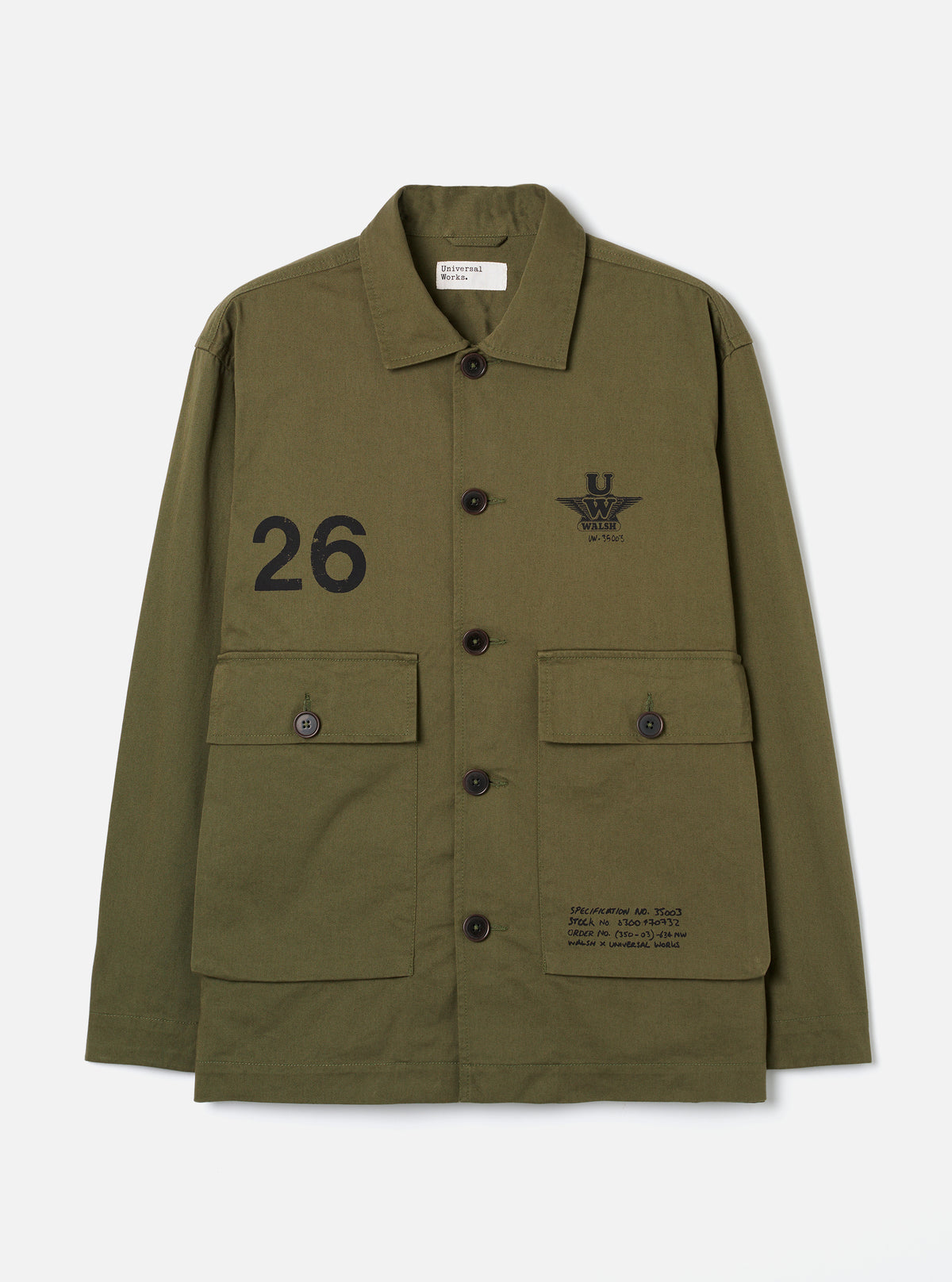 A male model stands against a plain neutral backdrop wearing the Walsh x Universal Works Light Olive Twill Troopers Jacket. The front-facing image highlights the light olive green cotton twill material, button front, and topstitching.