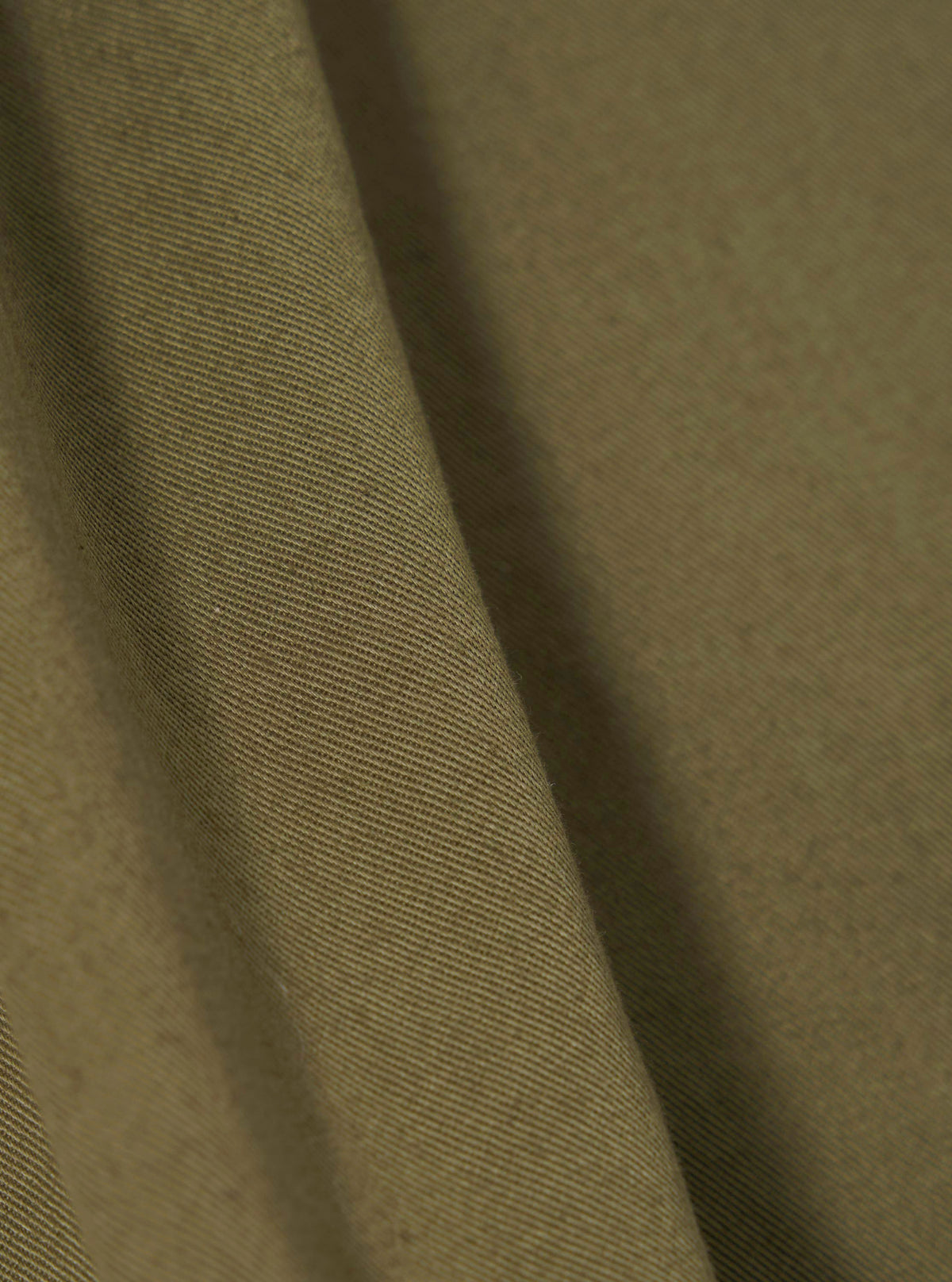 A fabric swatch showing a close-up texture view of the Walsh x Universal Works Light Olive Twill Troopers Jacket on a clean white background. The shot highlights the fine weave and light olive green cotton twill fabric.