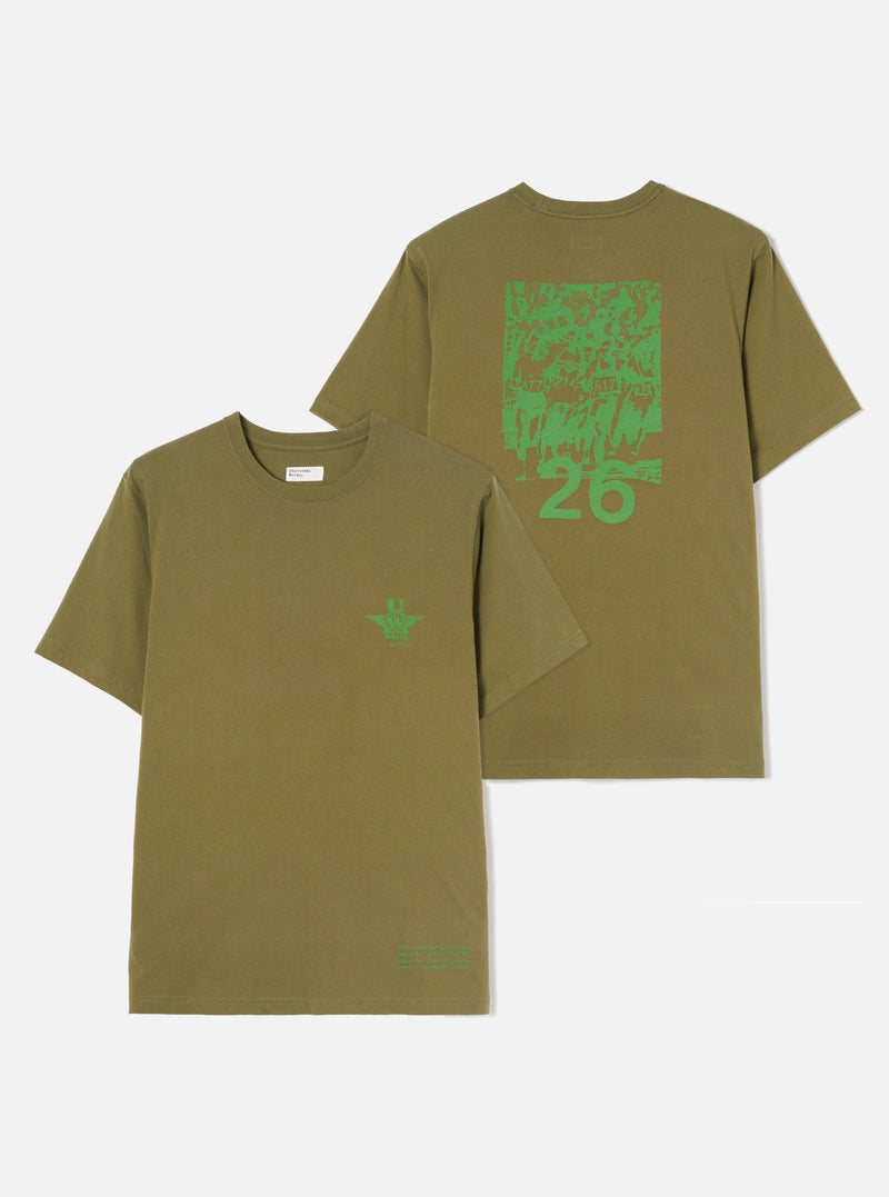 An angled view of the Walsh x Universal Works Olive Single Jersey T Shirt against a plain studio backdrop. Prominent features include the chest print detailing, relaxed fit, soft cotton weave, and warm olive green tone.