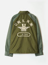 Front view with snap buttons open of the Walsh x Universal Works Olive Flight Nylon Club Coach Jacket against a plain background. The shot displays the inner lining, collar shape, welt pockets, and smooth olive green nylon material.