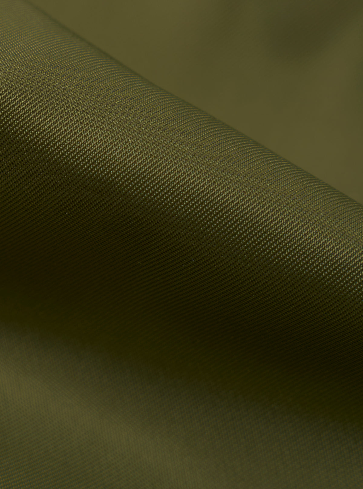 Extreme close-up shot of the Walsh x Universal Works Olive Flight Nylon Club Coach Jacket fabric. The image focuses on the fine weave texture, smooth olive green polyamide material, precise stitching, and subtle surface sheen.