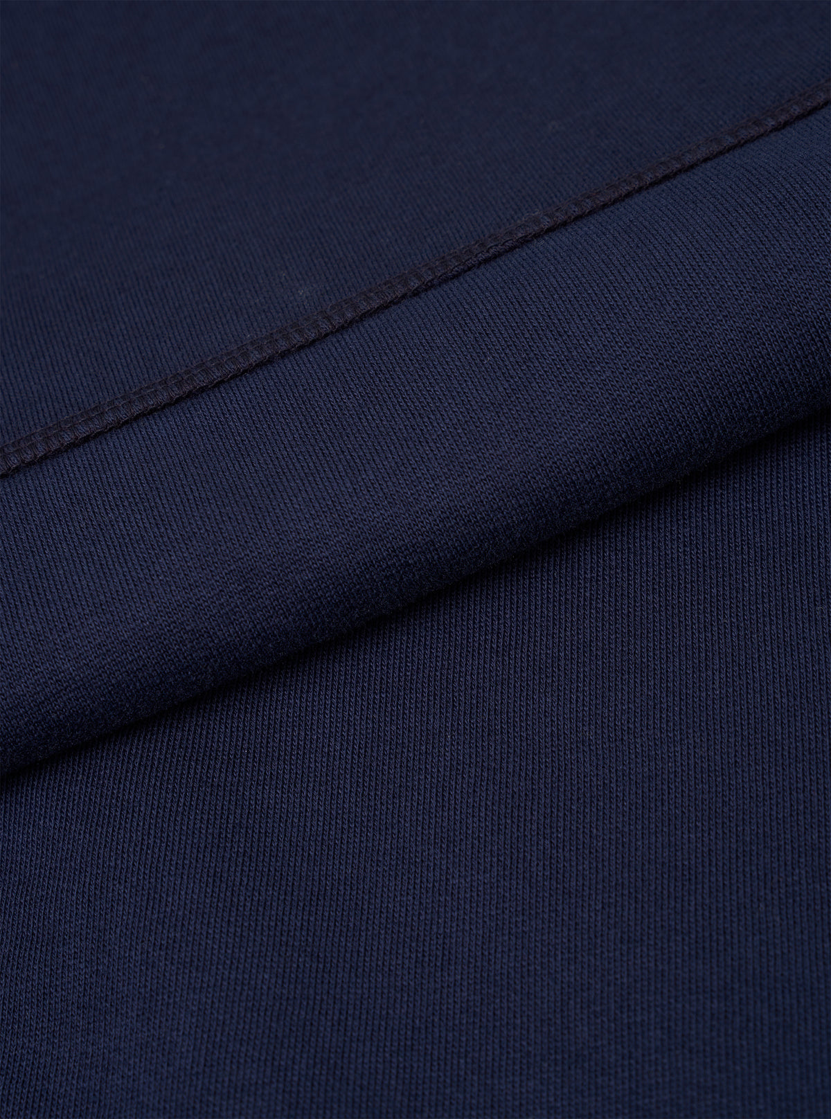 A macro fabric swatch shot of the Walsh x Universal Works Navy Brushback Sweat Panelled Loose Sweatshirt. The image highlights the rich dark navy color, soft cotton fleece weave texture, and high-quality knit finish in close detail.
