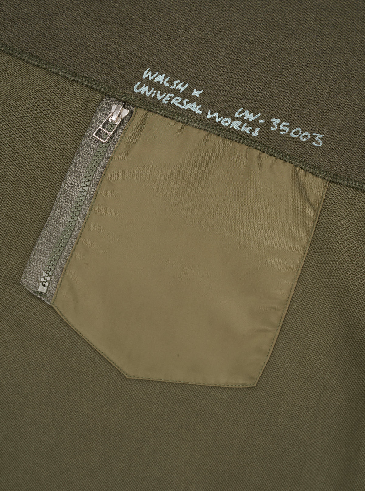Close-up front view of the Walsh x Universal Works Olive Brushback Sweat Panelled Loose Sweatshirt on a neutral background. The shot focuses on the intricate seam paneling, crewneck collar, and durable olive brushback cotton fleece.