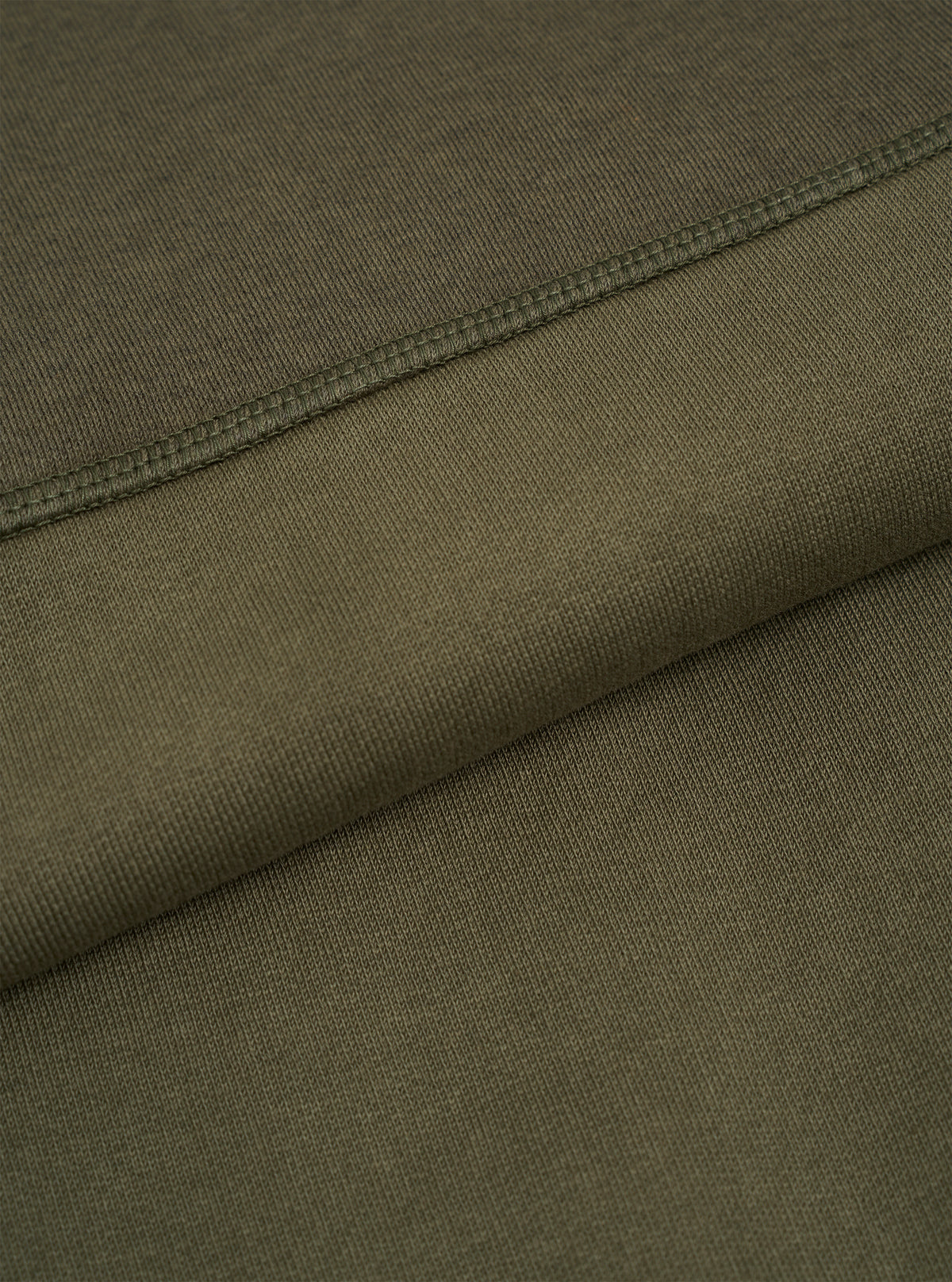 Macro fabric swatch image of the Walsh x Universal Works Olive Brushback Sweat Panelled Loose Sweatshirt. The close-up emphasizes the olive green knit texture, soft brushed cotton surface, and premium material quality.