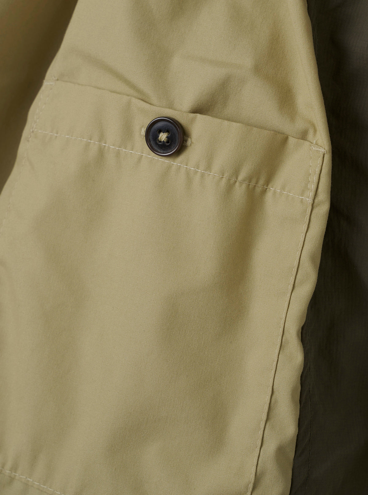 Close-up view of the Olive WR Recycled Nylon Peak Parka against a neutral background. The shot highlights fine fabric details, water-resistant recycled nylon texture, secure pocket fastenings, and high-quality stitching.
