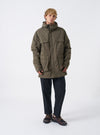A male model wears the Olive WR Recycled Nylon Peak Parka against a plain studio background. The image showcases the full-length relaxed fit, olive green tone, hooded front design, and functional front cargo pockets.