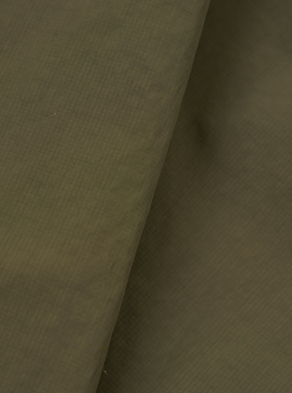 A close-up fabric swatch image of the Olive WR Recycled Nylon Peak Parka against a neutral studio background. The shot emphasizes the rich olive green colour, smooth weave, and water-resistant nylon texture.