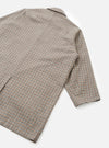 Flat lay detail shot of the taupe Lester Dogtooth Stan Coat on a white studio surface. The image shows the back panel and one long sleeve, highlighting the fine dogtooth weave in taupe, rust, navy and ecru. A notched collar is visible at the top. The cuff is unlined and plain.
