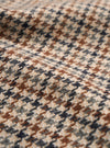 A close-up fabric swatch shot showing the material of the Taupe Lester Dogtooth Stan Coat against a light background. The image details the fine houndstooth weave in contrasting taupe, brown, and cream tones.