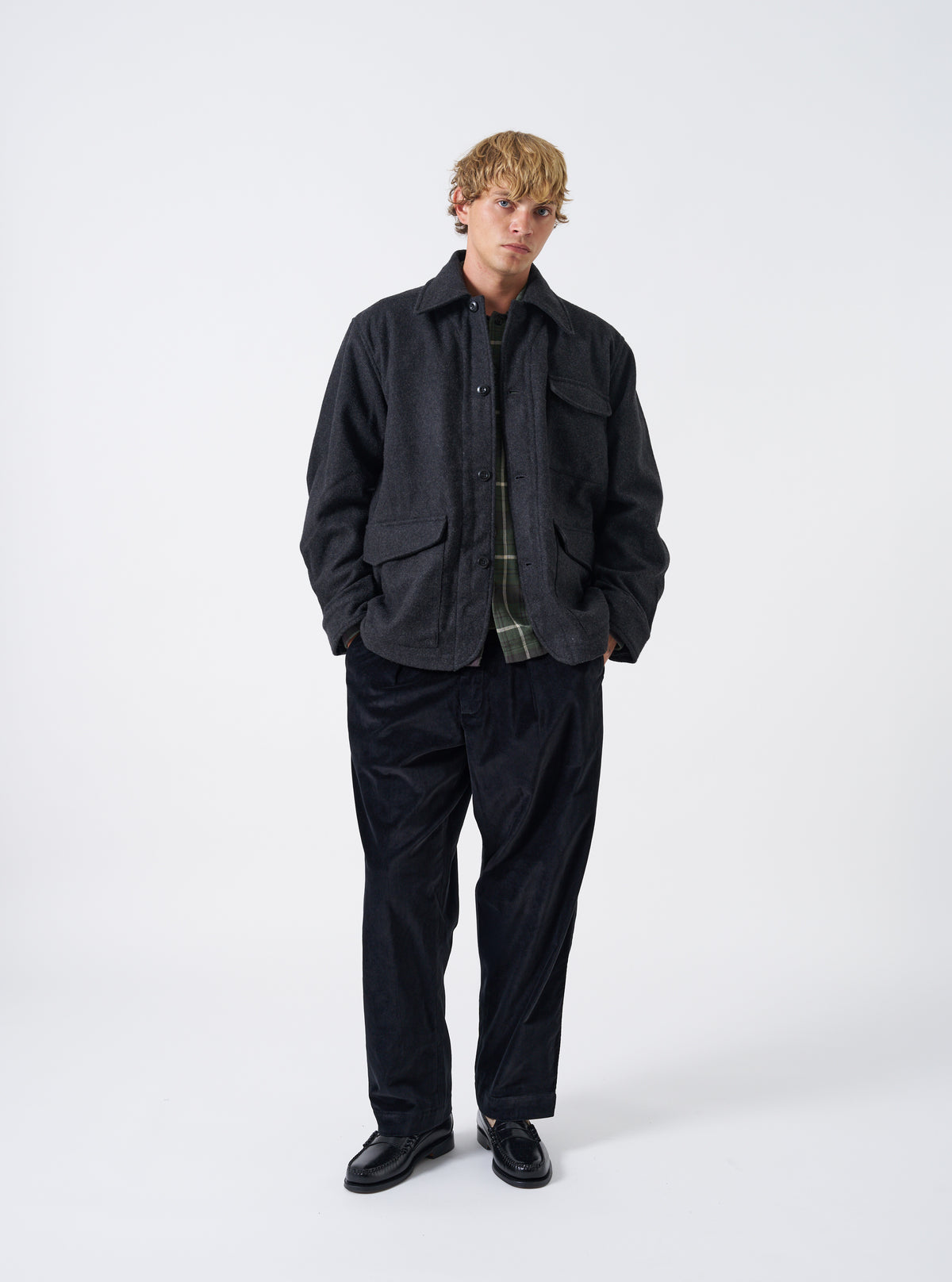 A male model poses against a plain studio background wearing the Grey Marl Mowbray Heavy Duty Jacket. The full front view highlights the textured grey wool-blend fabric, button closure, chest pocket, and collar.