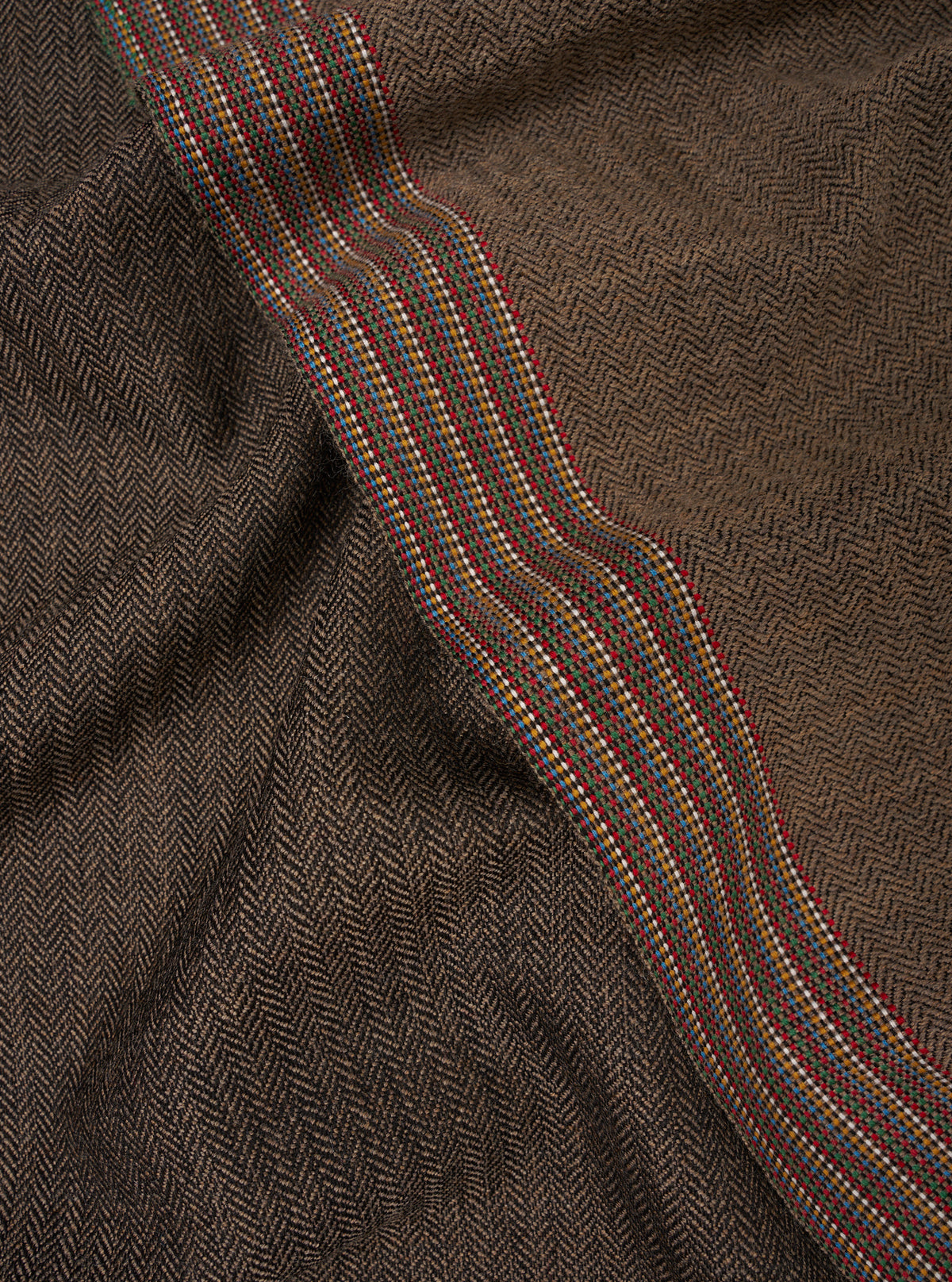A close-up swatch view of the Multi Reversible Wool Himalayan Scarf on a plain background. The image emphasizes the intricate multi-colored woven wool pattern, soft surface texture, and detailed yarn work.