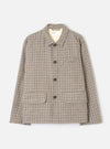 Taupe dogtooth Franck jacket laid flat on a light grey background. The wool-mix fabric features a multicolour dogtooth pattern in taupe, navy and rust. Point collar with a Universal Works woven label at the neck. Three dark horn buttons down the centre front. One chest welt pocket and two large patch pockets at the hem.