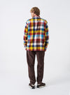 A male model stands against a plain neutral background wearing the Multi Check Evans Check Lucky Shirt. The image highlights the colorful check pattern, buttoned front, classic collar, and relaxed fit of the long-sleeved shirt.