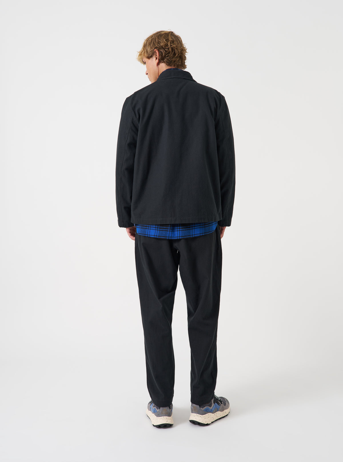 A model poses in the Black Brushed Moleskin Franck Jacket against a simple studio backdrop. The image emphasizes the soft brushed texture, side pockets, casual tailored fit, and deep black finish of the long-sleeved jacket.