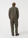 A back view of a model wearing the Universal Works Olive Brushed Moleskin Franck Jacket. The image highlights the smooth olive green cotton fabric across the shoulders, straight hemline, and clean tailoring set against a plain background.