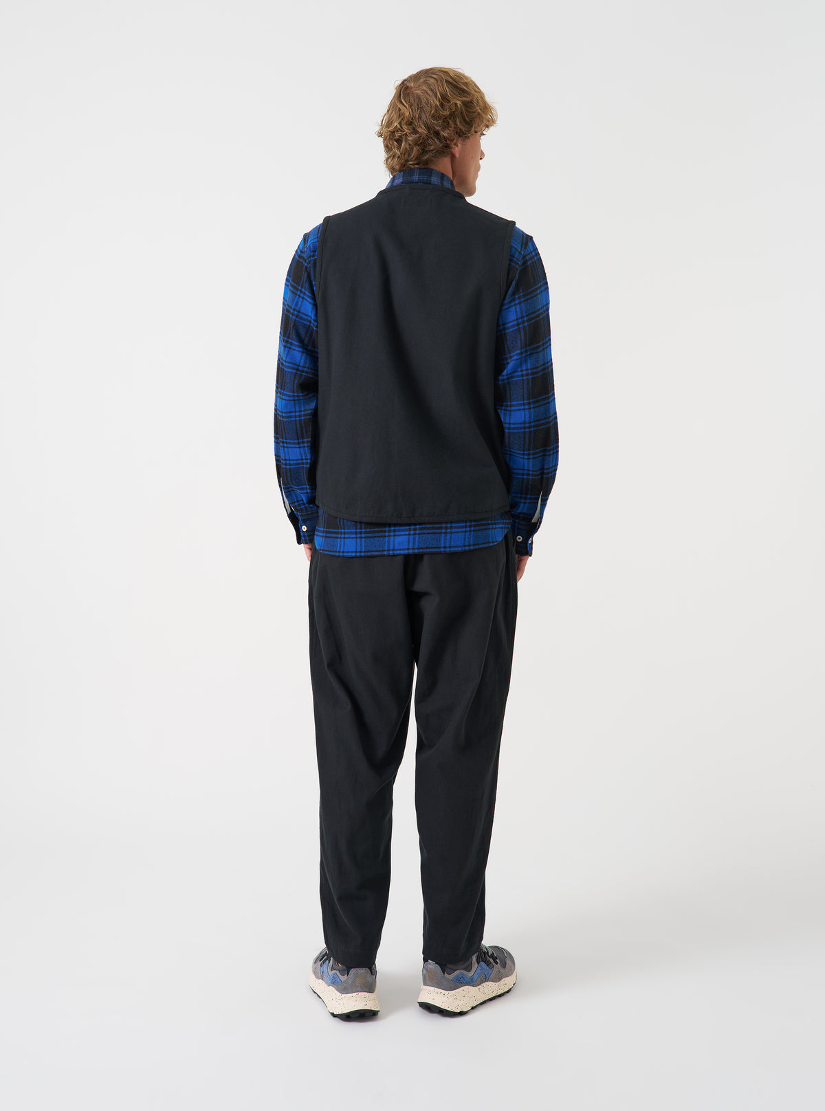 A back view of a model wearing the Universal Works Black Brushed Moleskin 4 Pocket Gilet. The image focuses on the rear panel of the black brushed cotton vest, showing the relaxed fit and neat stitching set against a plain neutral background.