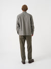 A back view of a model wearing the Universal Works Olive Brushed Moleskin Military Chino against a plain backdrop. The image displays the rear jetted pockets with button closures and the clean, tailored line of the olive trousers.