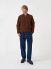 A model wearing the Universal Works Indigo Work Denim Super Chino, shown from the front against a plain background. The dark blue cotton denim trousers feature a wide loose leg fit, button fly, belt loops, and turn-up cuffed hems.
