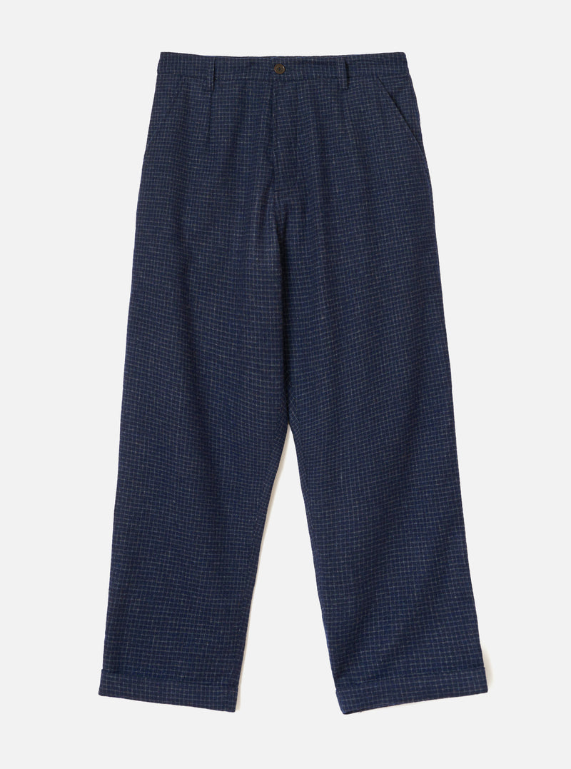 The Navy Check Bobby Wool Mix Super Chino is laid flat against a light grey backdrop. It displays a fine grey grid check pattern, a single bronze button closure, front pleats, slanted side pockets, zip fly, and turned-up cuffs at the hem.