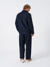 A back view of a model wearing the Navy Bob Wool Mix Bakers Overshirt. The image highlights the textured wool-blend navy fabric, straight hemline, and relaxed fit of the garment set against a plain backdrop.