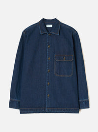 The Indigo Contrast Stitch Work Denim Fatigue Shirt is laid flat against a light grey studio backdrop. Features include a camp collar, five bronze buttons down the front placket, a chest patch pocket, and contrast orange topstitching.