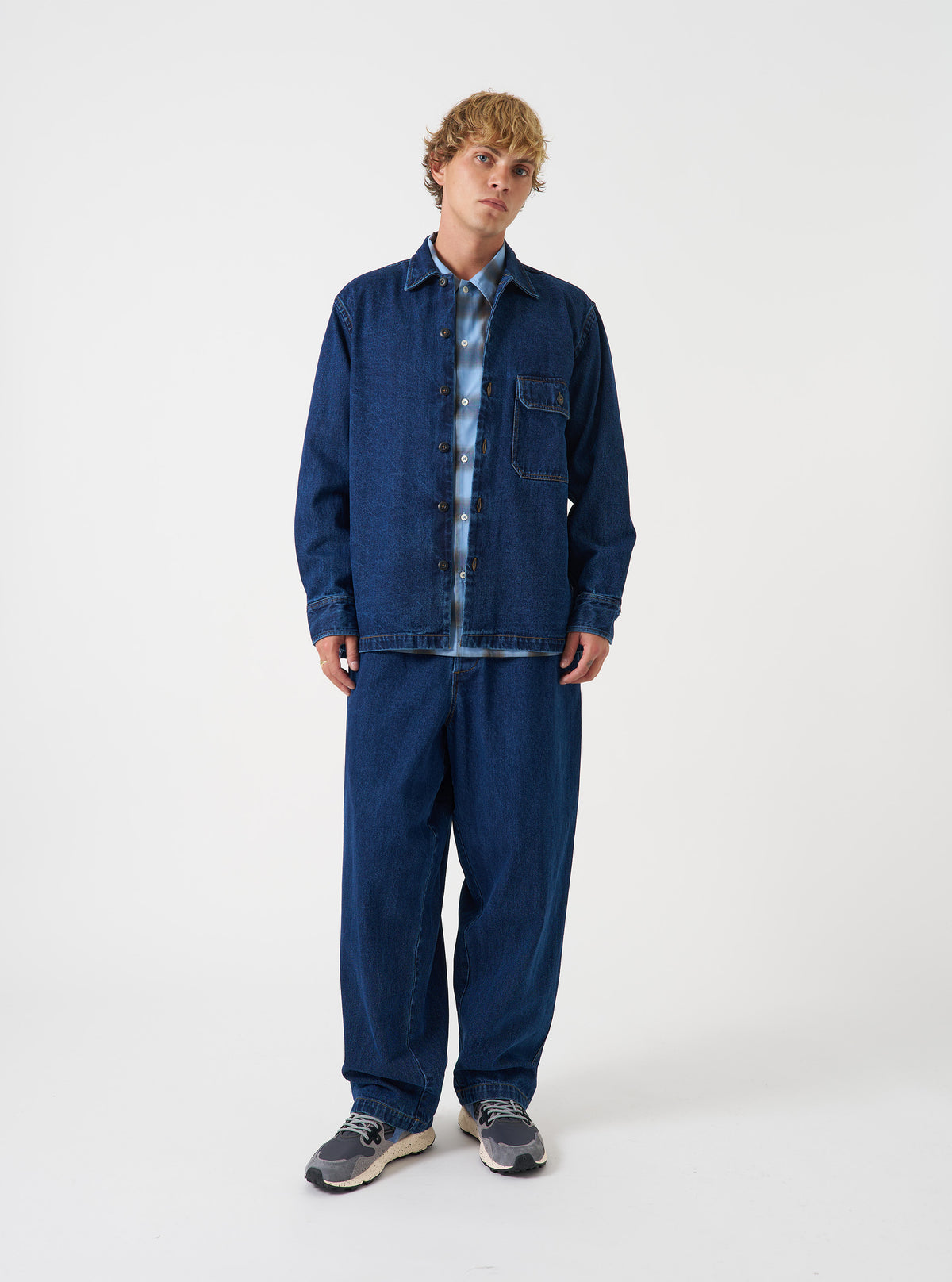 A model wearing the Indigo Contrast Stitch Work Denim Fatigue Shirt, shown from the front. The dark indigo cotton denim overshirt features prominent contrast stitching and large chest pockets against a plain backdrop.