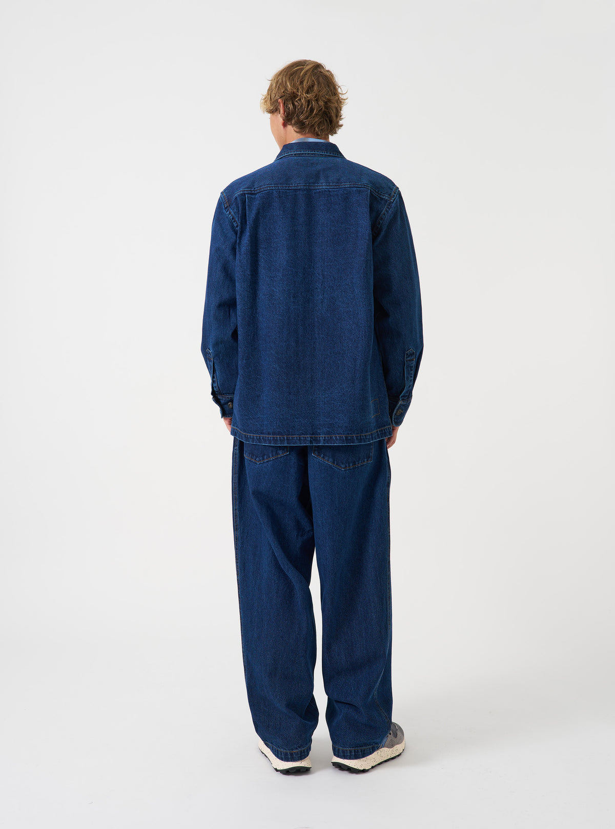 A rear view of a model wearing the Indigo Contrast Stitch Work Denim Fatigue Shirt. The image highlights the dark blue denim construction, contrast seam details, and relaxed fit set against a plain neutral background.