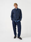 A model wearing the Indigo Future Denim Troopers Jacket, captured from the front. The indigo organic cotton jacket features a button front closure, classic collar, and multiple flap patch pockets against a plain background.