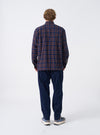 A back view of a model wearing the Navy/Brown Young Check CPO Shirt. The image shows the blue and brown checked cotton pattern across the back shoulders and straight hem against a plain neutral backdrop.
