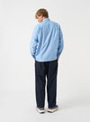 A rear view of a model wearing the Blue Stripe Refab Compact Cotton Lucky Shirt. The image highlights the blue and white vertical stripe pattern across the back and shoulder yoke set against a plain neutral background.