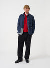 A model wearing the Universal Works Indigo Future Denim OG Bakers Chore Jacket, shown from the front. The dark blue denim jacket features a classic collar, central button fastening, and multiple front patch pockets against a plain background.