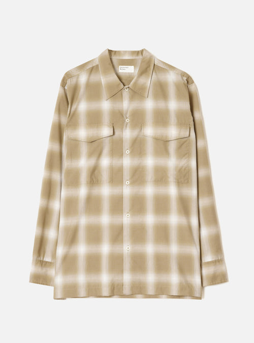 Sand and cream ombre check long-sleeve shirt laid flat on a light grey studio backdrop. Features a pointed collar, full-length button placket with cream buttons, two flap chest pockets, and buttoned cuffs. Universal Works woven label visible at the neckline.