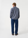 A back view of a model wearing the Universal Works Blue/Brown Parker Check Attendant Shirt. The photo highlights the brown and blue check pattern across the back, straight hemline, and casual silhouette set against a plain backdrop.