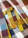 A close-up image of the Universal Works Multi Check Evans Check Long Dressing Gown on a plain background, showing the rich multi-check woven cotton fabric detail, soft shawl lapel collar, and detailed waist tie stitching.