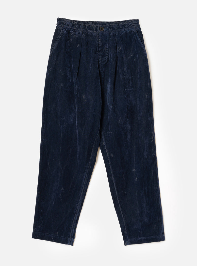 A front studio view of the Navy Flock Chambray Pleated Track Pant set against a plain backdrop. The dark navy cotton trousers feature a relaxed fit, pleated front detail, tapered leg cut, and a comfortable elasticated drawstring waist.