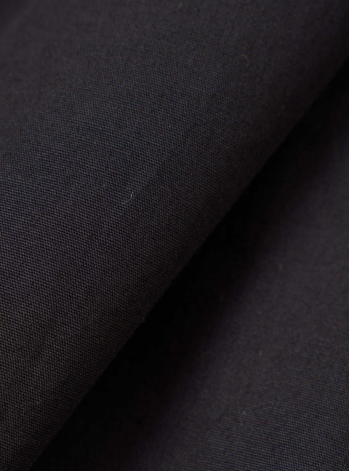 Close-up fabric swatch image of the Black Broadcloth Boxer Shorts by Universal Works. Displays the weave, soft texture, and solid dark shade of the black cotton broadcloth material against a neutral background.