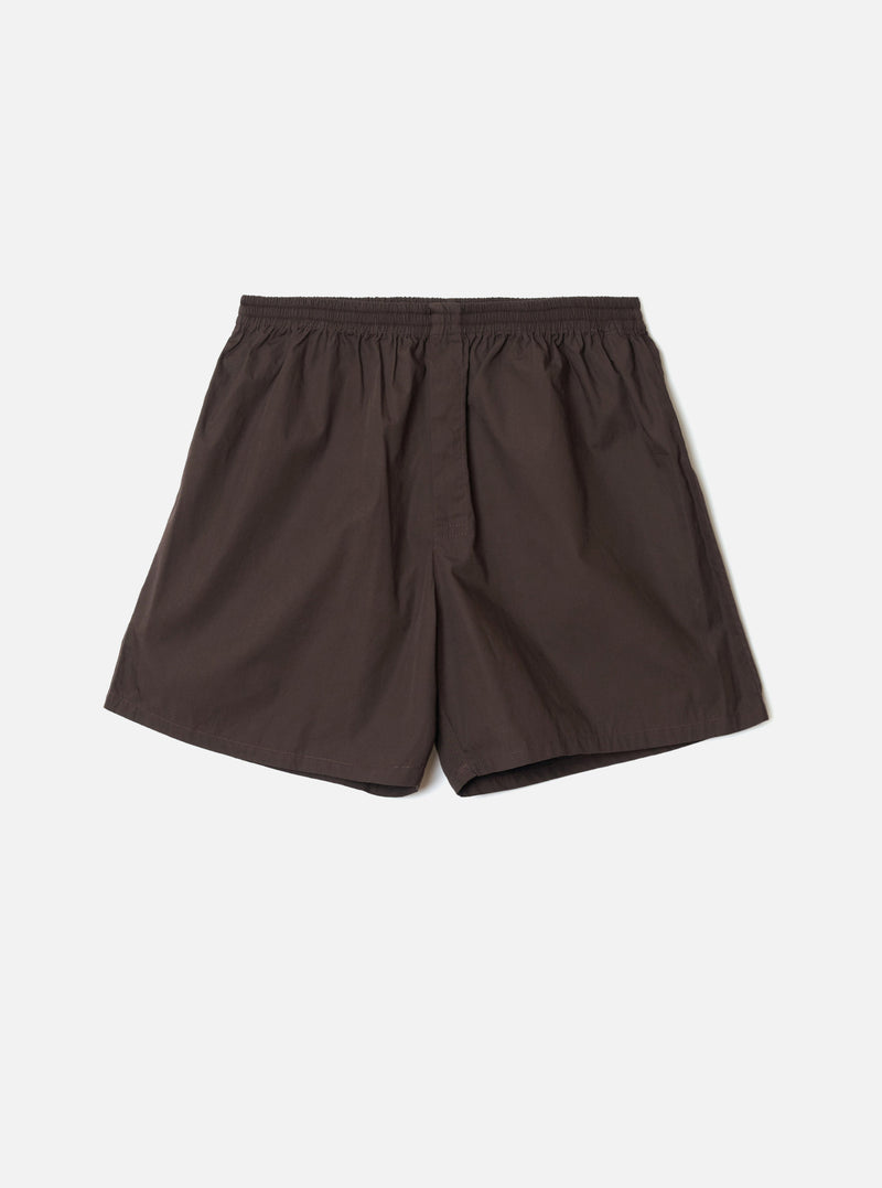 Front view of the Universal Works Brown Broadcloth Boxer Shorts shown on a plain backdrop. Features rich brown cotton broadcloth fabric, smooth elastic waistband, side stitching, and classic relaxed fit.
