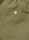 Rear view of the Universal Works Olive Broadcloth Boxer Shorts set against a plain white background, featuring a single small rear patch pocket, elasticated waist, and clean tonal stitching.