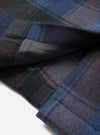 A detailed view of the Universal Works Navy/Brown Berlin Wool Check Account Coat shown on a plain background, highlighting the concealed front button closure, point collar, and structured shoulders.