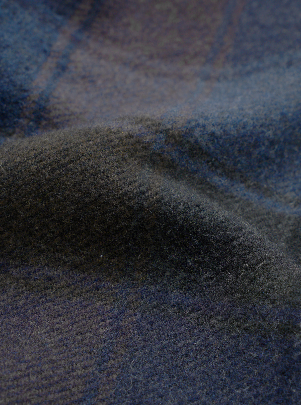 A close-up fabric swatch image of the Universal Works Navy/Brown Berlin Wool Check Account Coat, showcasing the rich textured weave of the navy, brown, and grey checkered wool blend fabric.