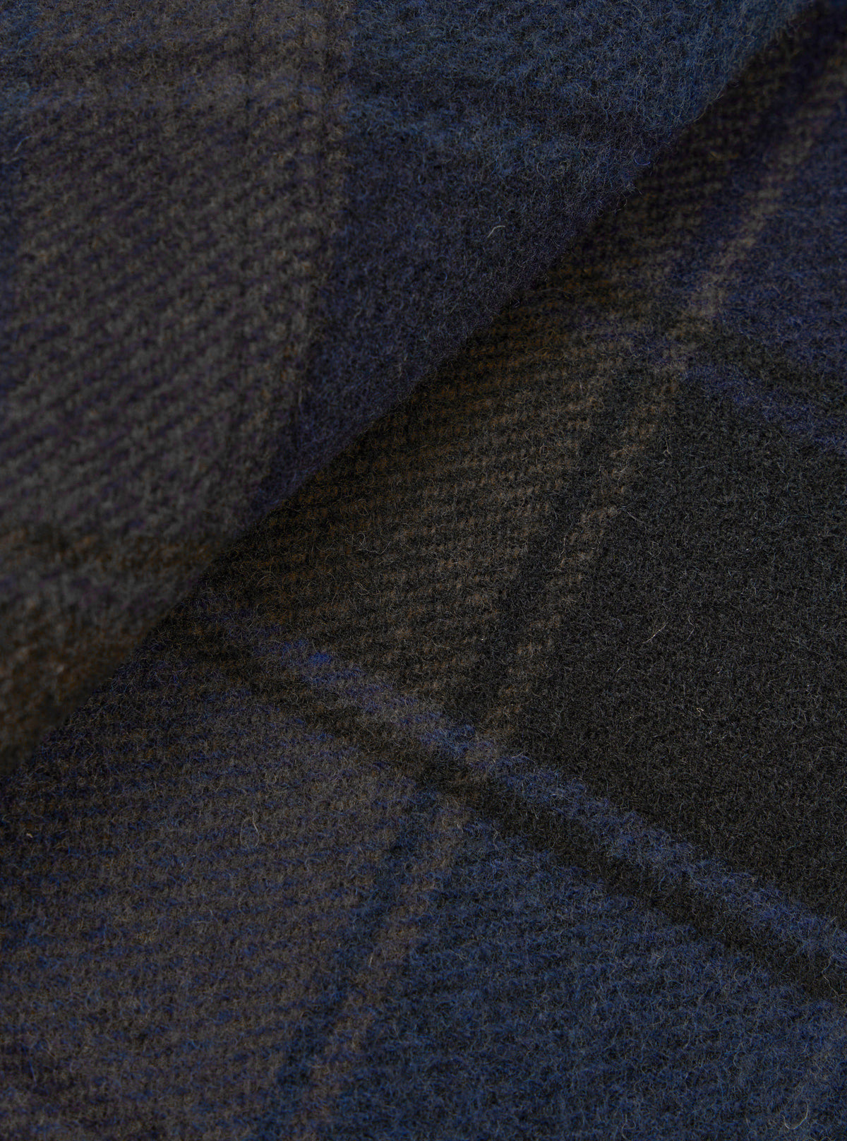 A close-up fabric swatch shot showing the brushed surface and detailed weave pattern of the Universal Works Navy/Brown Berlin Wool Check OG Bakers Chore Jacket in rich navy and brown tones.