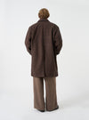 A back view of a model wearing the Navy/Brown Wool Tweed Mix Stan Coat. The image highlights the relaxed drop of the long tweed coat, smooth shoulder seam construction, and straight hemline set against a neutral studio backdrop.